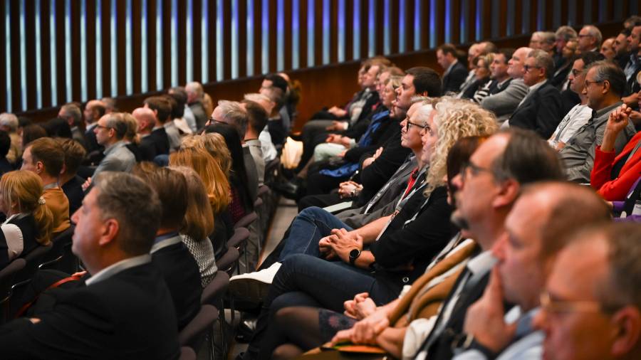 Publikum sitzt dicht nebeneinander und hört konzentriert einem Vortrag zu
